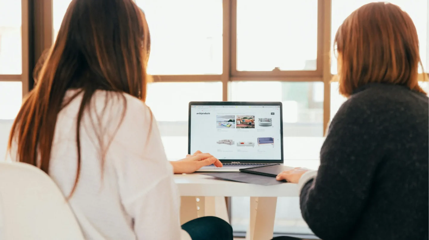 Two women sitting together reviewing a website on a laptop