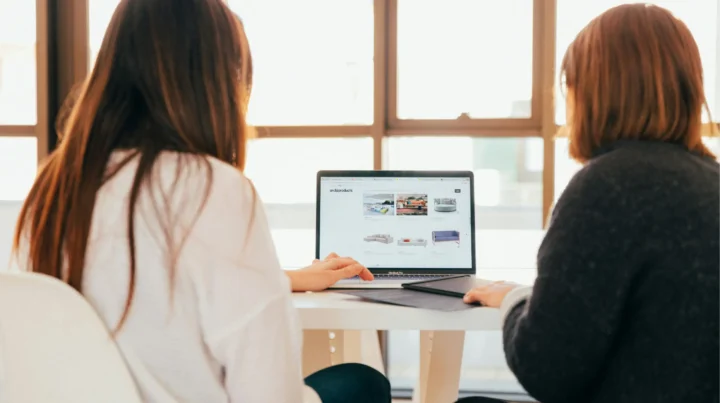 Two women sitting together reviewing a website on a laptop